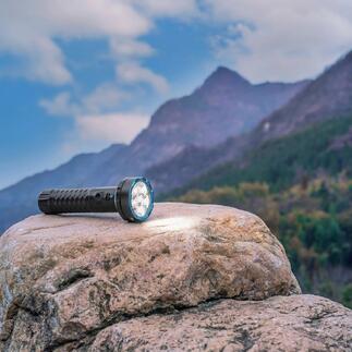 Lampe de poche bidirectionnelle de 5000 lumens sur une pierre avec un paysage montagneux.