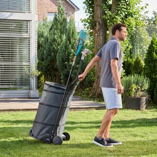 Homme tirant un chariot de jardin pliable avec des feuilles dans le jardin.