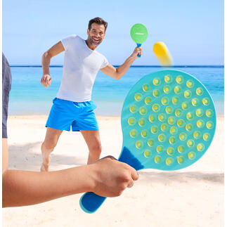 Homme jouant sur la plage avec une raquette ovale et frappant la balle.