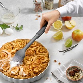 Main avec un pinceau à pâtisserie qui badigeonne un gâteau à la cannelle chaud.