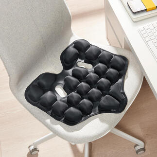 Coussin ergonomique noir sur une chaise.