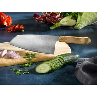 Couteau Nakiri en damas sur une planche en bois, entouré de légumes frais.