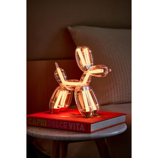 Lampe en forme de chien en ballon sur un livre, lumière blanche chaude.