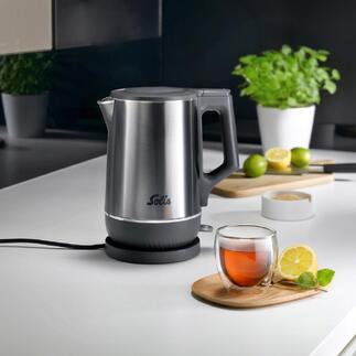 Bouilloire double avec finition en acier inoxydable et thé dans un bol en verre sur la table.