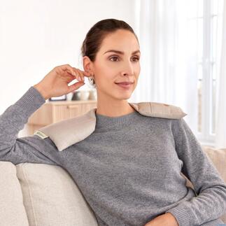Femme portant un chauffe-épaule assise confortablement sur le canapé
