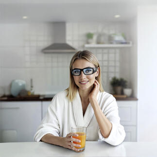 Femme portant des lunettes de lumière dans la cuisine avec une boisson.