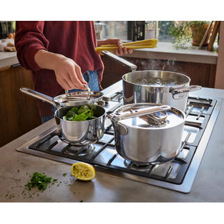 Set de casseroles avec poignée pliable, une casserole et deux casseroles avec des légumes sur la cuisinière.