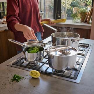 Set de casseroles avec poignée pliable, une casserole et deux casseroles avec des légumes sur la cuisinière.