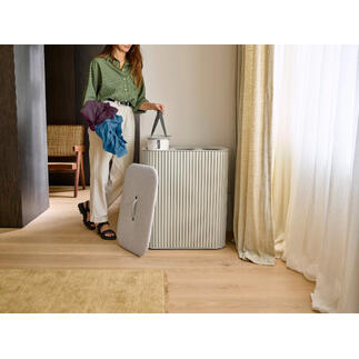 Femme avec des vêtements colorés debout à côté d'un collecteur de linge.