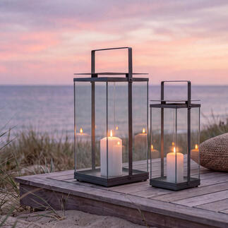 Deux lanternes design sur une terrasse en bois à la plage au coucher du soleil.