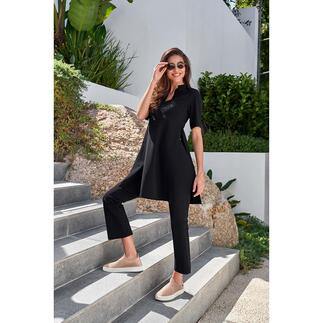 Femme portant une tunique noire et un pantalon bootcut sur les escaliers.