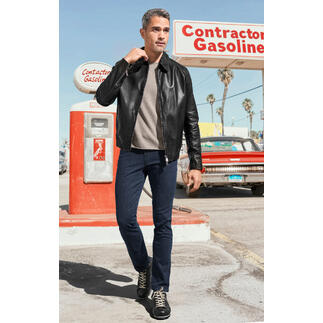 Homme en blouson soft en cuir de veau noir et pull beige devant une station-service.