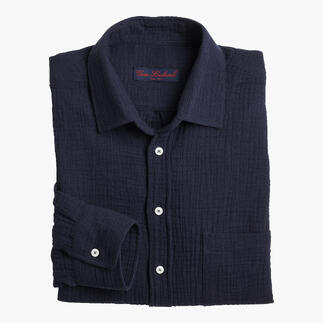 Chemise en mousseline navy bien pliée sur un fond blanc.