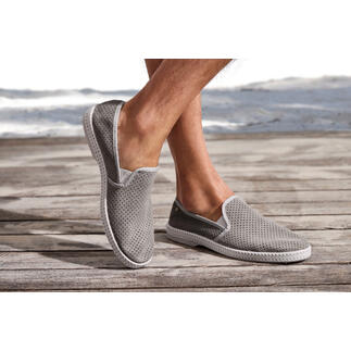 Mocassins en cuir gris avec surface perforée sur terrasse en bois.