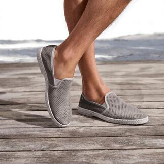 Mocassins en cuir gris avec surface perforée sur terrasse en bois.