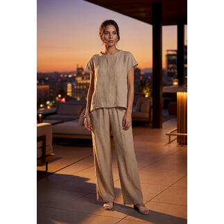 Femme portant une blouse couleur sable et un pantalon large sous la lumière du soir.