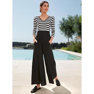 Femme portant un t-shirt magique rayé avec un pantalon noir, debout devant une piscine.