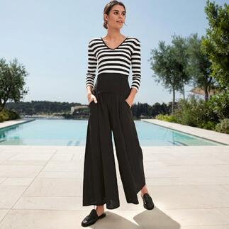 Femme portant un t-shirt magique rayé avec un pantalon noir, debout devant une piscine.