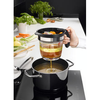 Main utilisant un tamis pour verser du bouillon de légumes dans une casserole, avec une cuisine en arrière-plan.