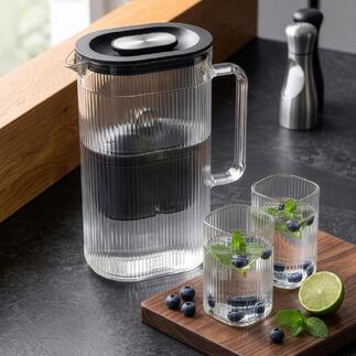 Carafe filtrante avec un verre supplémentaire et des herbes fraîches.