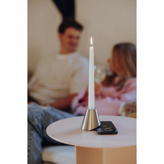 Bougie dans un support en métal sur une table, arrière-plan avec des personnes.