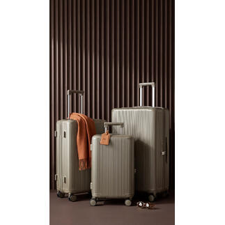 Trois valises rigides de différentes tailles sur fond sombre
