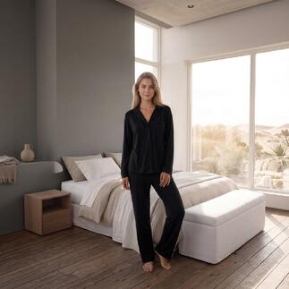 Femme debout dans un pyjama noir dans une chambre.