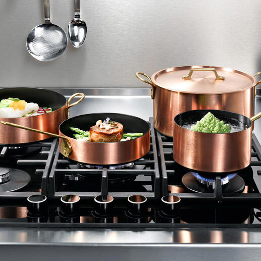 Casseroles en cuivre à induction sur une cuisinière avec plusieurs casseroles et une poêle.