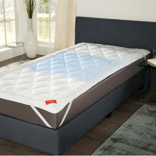 Hefel Cool surmatelas sur un lit dans une pièce lumineuse.