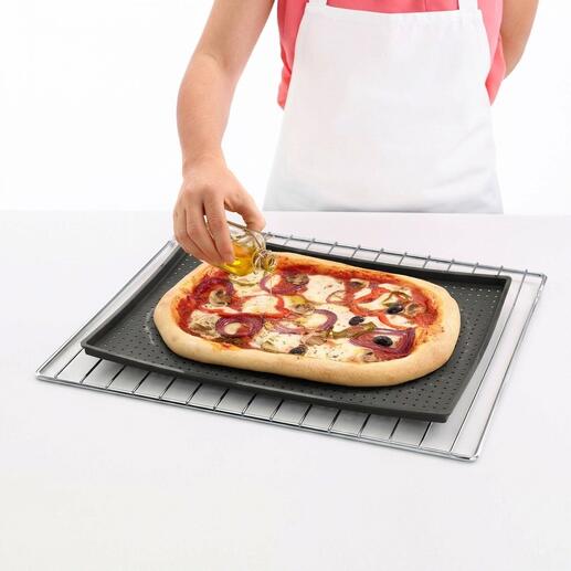 Personne ajoutant de l'huile sur une pizza sur un tapis de cuisson croustillant