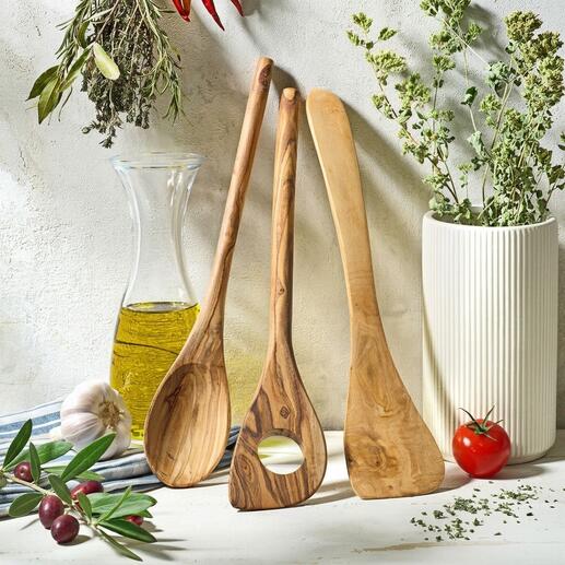 Ustensiles de cuisine en bois d'olive de trois pièces sur une table rustique avec des herbes.