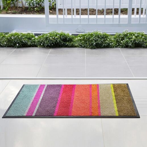 Tapis d'entrée coloré avec des rayures devant une surface vitrée