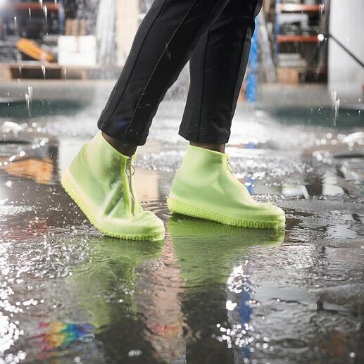 Personne avec des surchaussures de pluie vertes claires se tient dans une flaque.