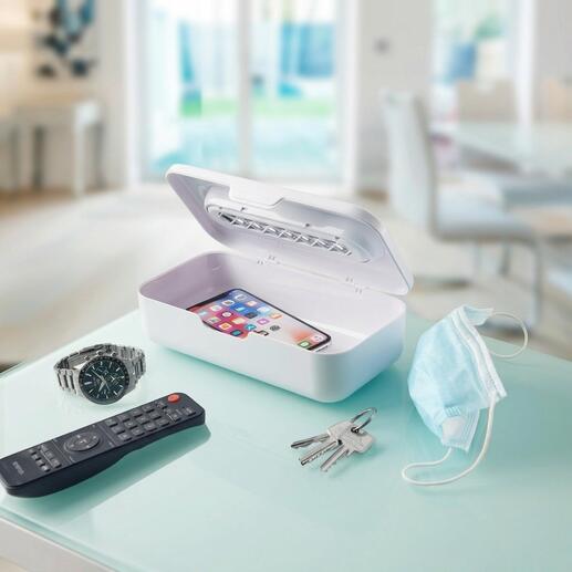 Stérilisateur UV-C 2-en-1 avec smartphone et objets du quotidien sur une table.
