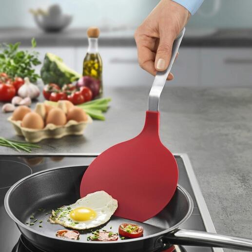 Spatule XXL en action, soulevant un œuf au plat de la poêle.