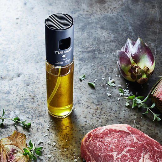 Vaporisateur d'huile avec filtre à côté d'un steak cru et des fleurs artificielles sur une table rustique.