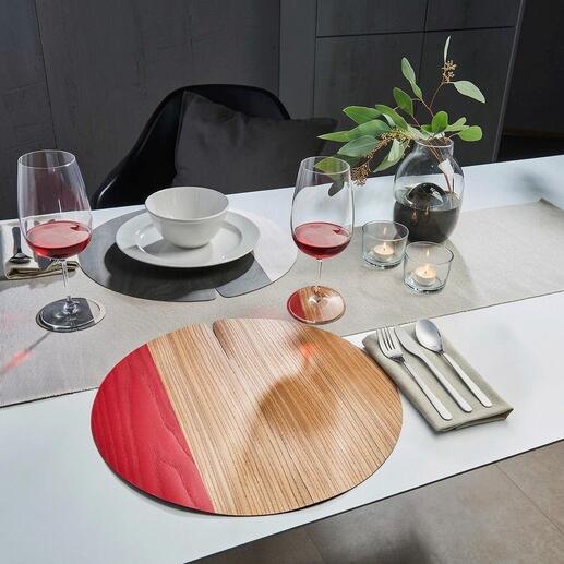 Sets de table en bois avec rouge et bois clair sur une table dressée avec des verres et de la vaisselle.