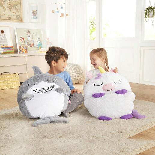 Deux enfants assis à côté d'un sac de couchage coloré en licorne et en requin.