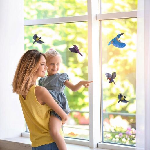 Mère avec enfant devant une fenêtre avec des autocollants d'oiseaux