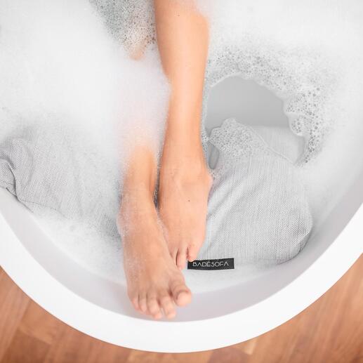 Gros plan de pieds dans la mousse et coussin de bain dans la baignoire.