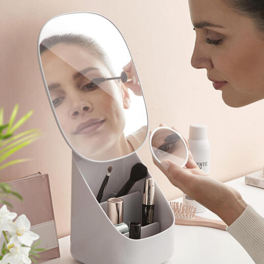 Femme se maquillant devant un miroir de maquillage avec organisateur intégré sur une table.