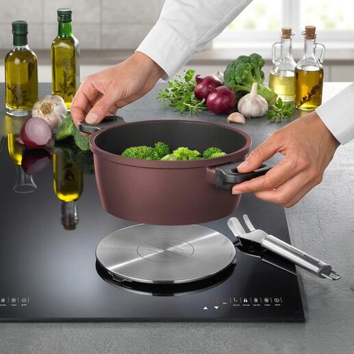 Plaque d'adaptation à induction avec brocoli dans une casserole à côté.