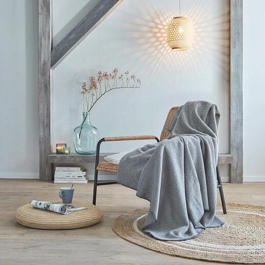 Couverture en laine polaire sur une chaise dans un salon moderne.