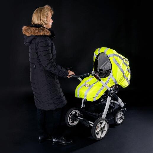 Femme portant un gilet avertisseur pour poussette, bandes réfléchissantes visibles, sur un fond sombre.