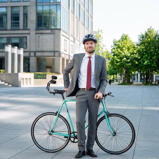 Homme en costume se tenant avec un vélo et le support arrière Tshobo à l'extérieur.