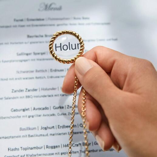 Main tenant une loupe à une chaîne dorée au-dessus d'un menu.