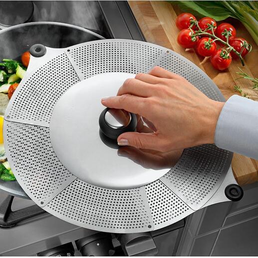 Main plaçant un couvercle anti-éclaboussures universel sur une casserole avec des légumes et un œuf sur une cuisinière
