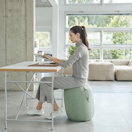 Femme assise sur un tabouret d'équilibre gonflé à l'air et travaillant sur un ordinateur portable