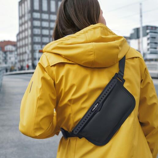 Femme en manteau jaune portant un sac à bandoulière noir sur l'épaule.