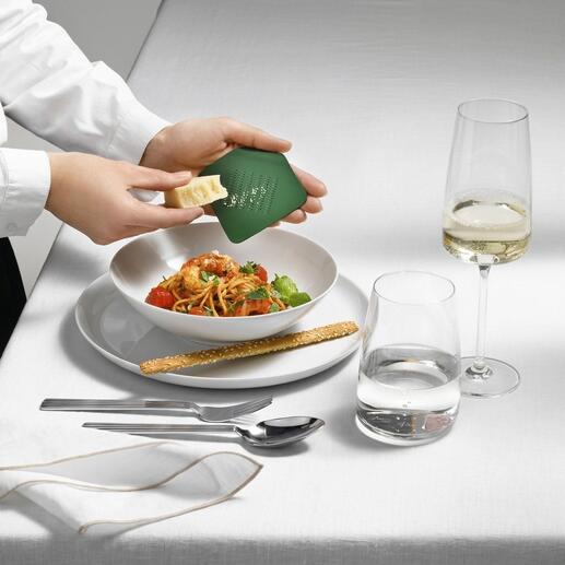 Personne tenant une râpe design Irogami au-dessus d'une assiette de salade de pâtes.